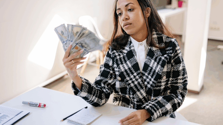 woman holding hundred dollar bills looking at her hand holding money | itsmymoney